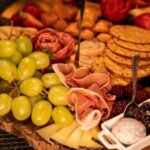 Elegant charcuterie board featuring grapes, cheese, prosciutto, and crackers.