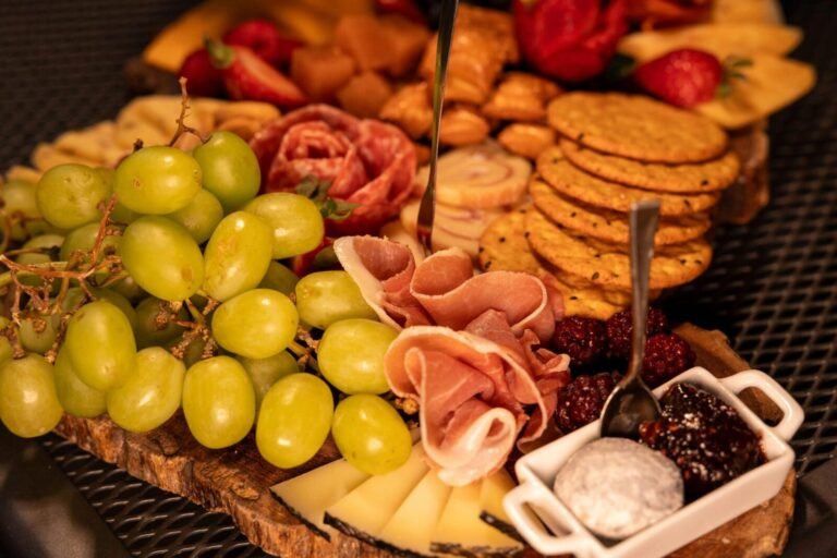 Elegant charcuterie board featuring grapes, cheese, prosciutto, and crackers.