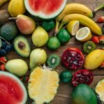 A colorful assortment of fresh fruits including bananas, strawberries, and watermelon arranged on a wooden table.