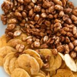Close-up image of crispy banana chips and sweet honey roasted peanuts on a ceramic plate.